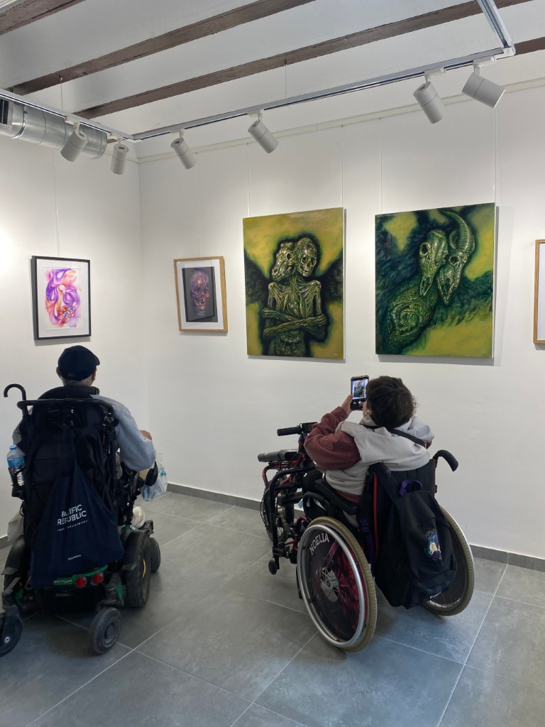 Grupo de asistentes observando una de las obras en la Sala de Exposiciones.